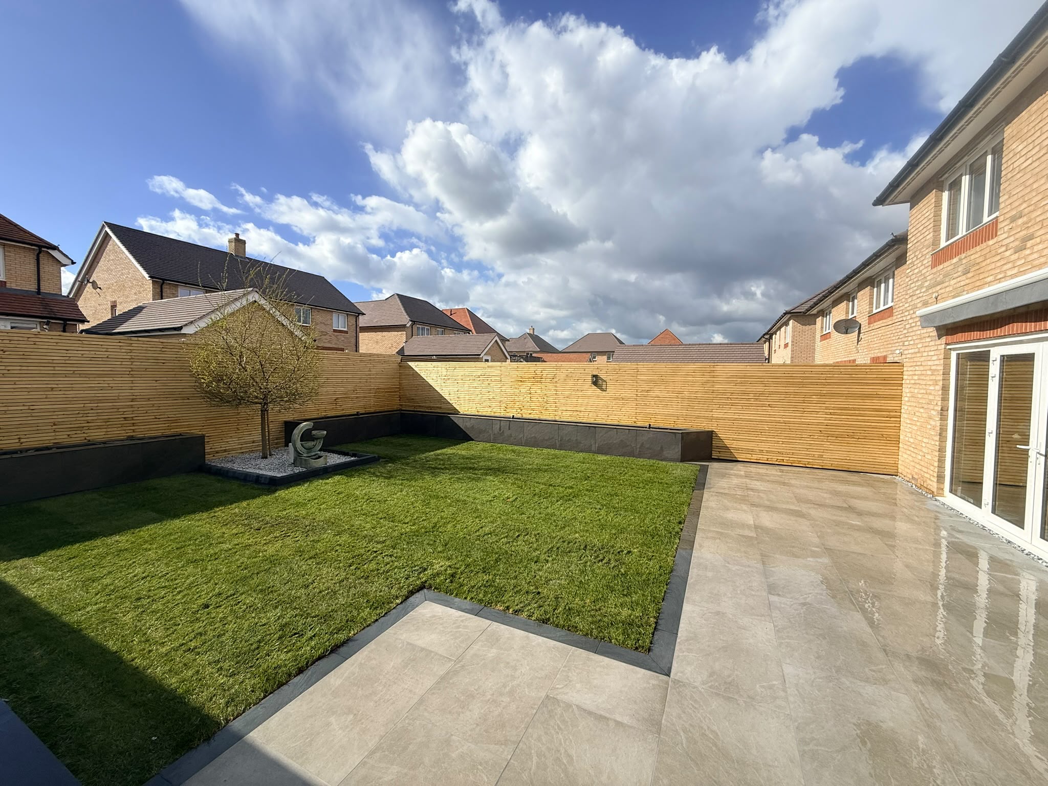 After: Modern garden retreat with slatted fencing, porcelain paving and feature tree on the Redrow estate, Witham