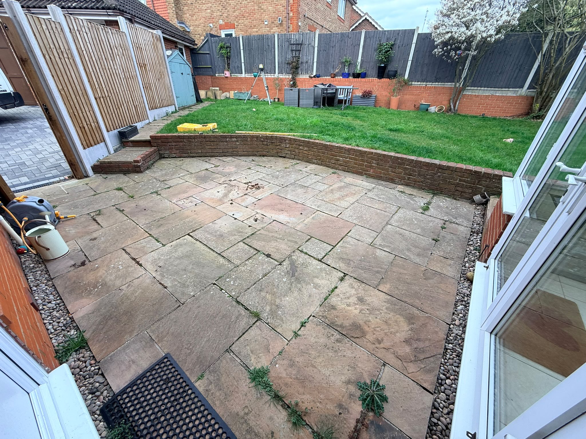 Before: Aging, uneven sandstone patio and tired lawn in Chelmsford